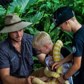 Children patting a snake that is being presented by a reptile keeper