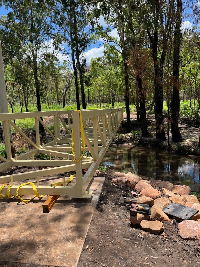 Pedestrian bridge being installed over waterway .
