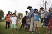 A group of kids outdoors with a man in a blue shirt and hat, enjoying activities at Kakadu Bird Week